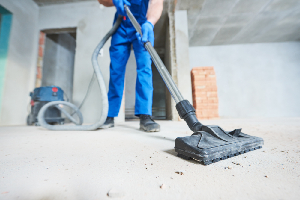 Hommesur un chantier aspirant des petits gravats avec un aspirateur industriel