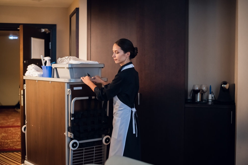 Une Femme De Ménage Tient Un Panier Avec Des Produits De Nettoyage Et Se  Prépare à Nettoyer Une Chambre D'hôtel